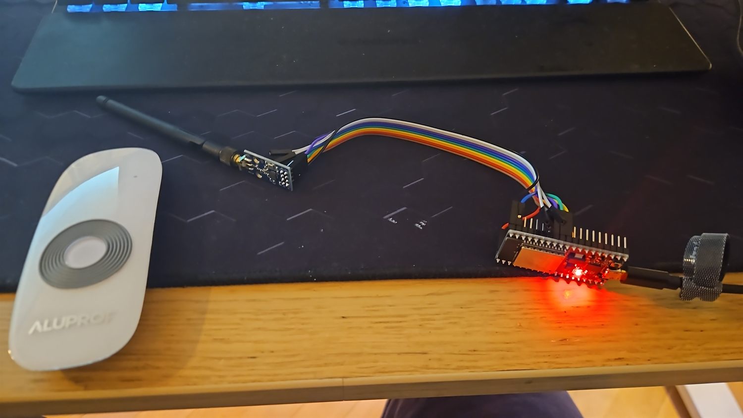 ESP32 s CC1101 modulem a SMA anténou, vedle originální ovladač Aluprof DC305A